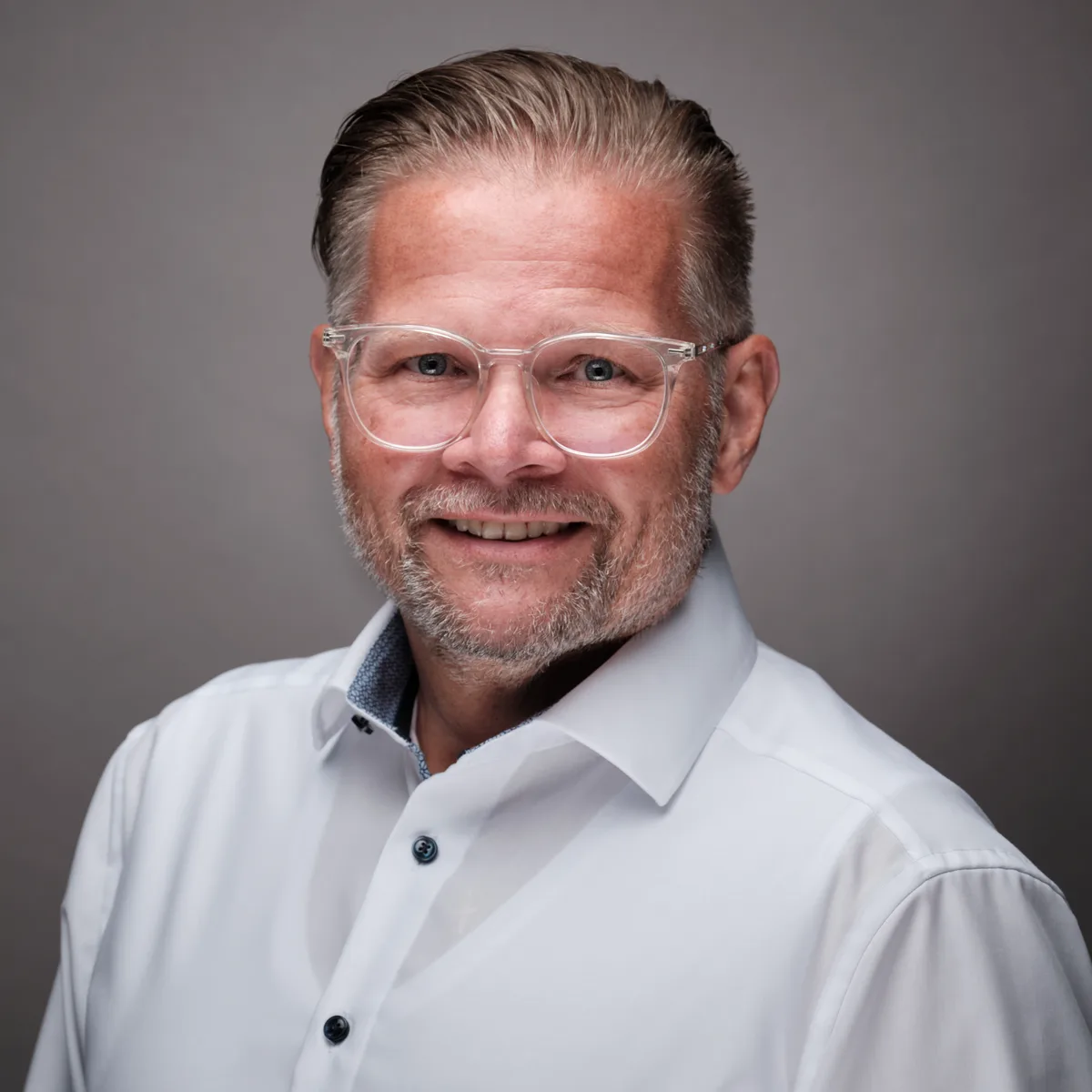 Porträtbild von Exista-CEO Thomas Fischer. Er trägt ein offenes weisses Hemd und eine transparente Kunststoffbrille.